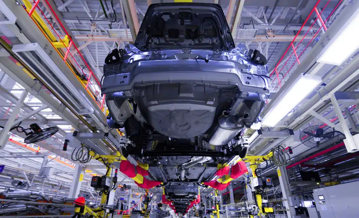 Electric vehicle manufacturing line with busbar integration in progress.