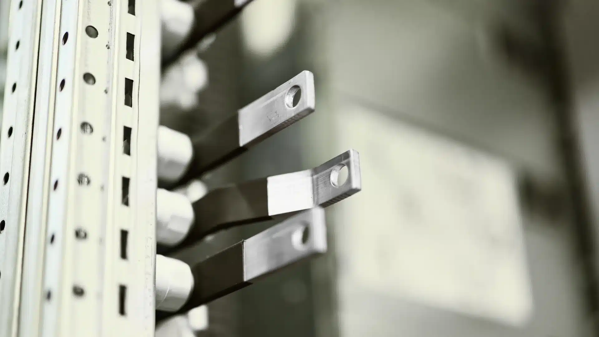 Flat metal busbar terminals with drilled fixing holes mounted inside an electrical distribution panel.