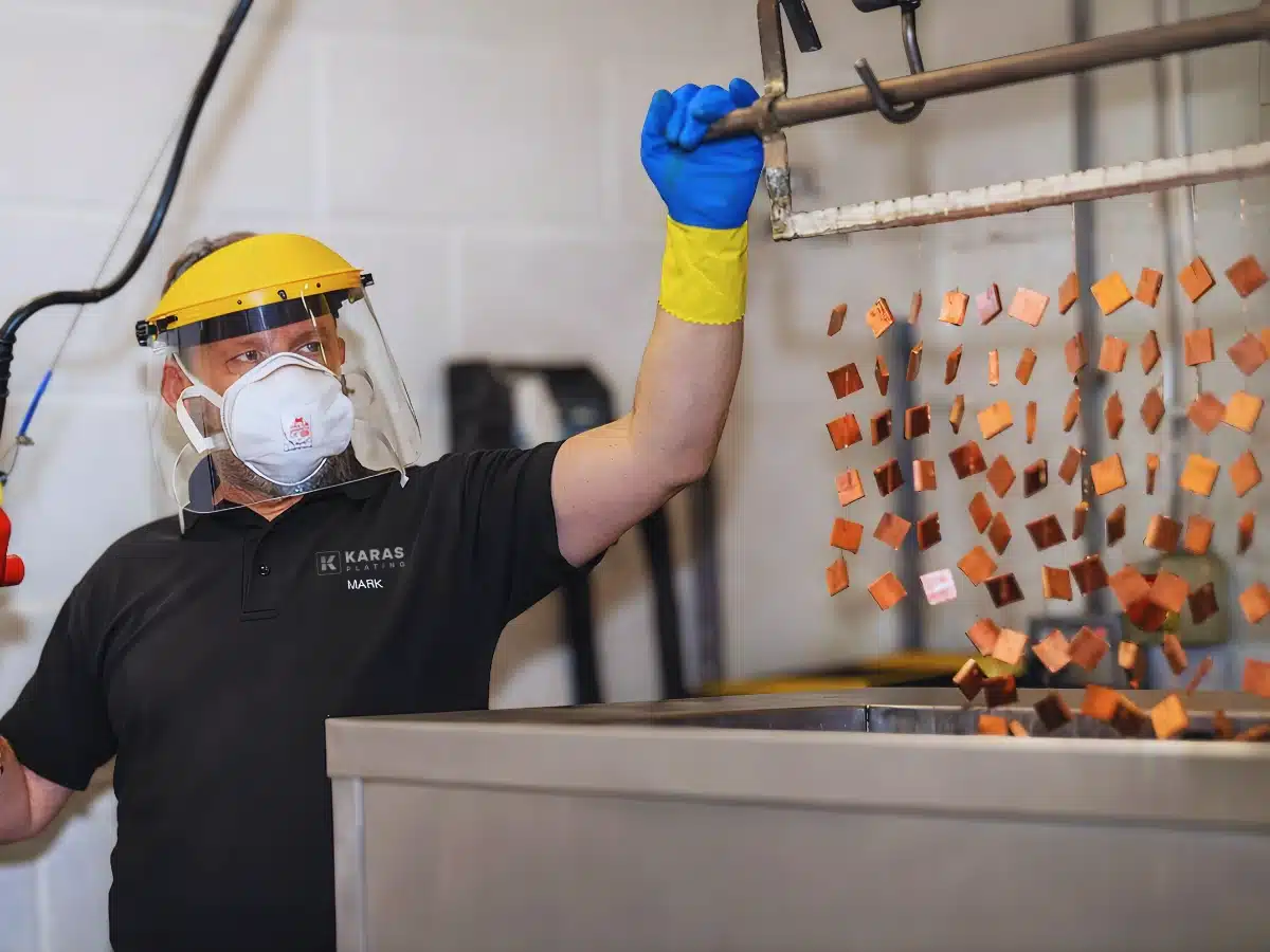 Technician electroplating copper components for solar applications in an industrial plating tank